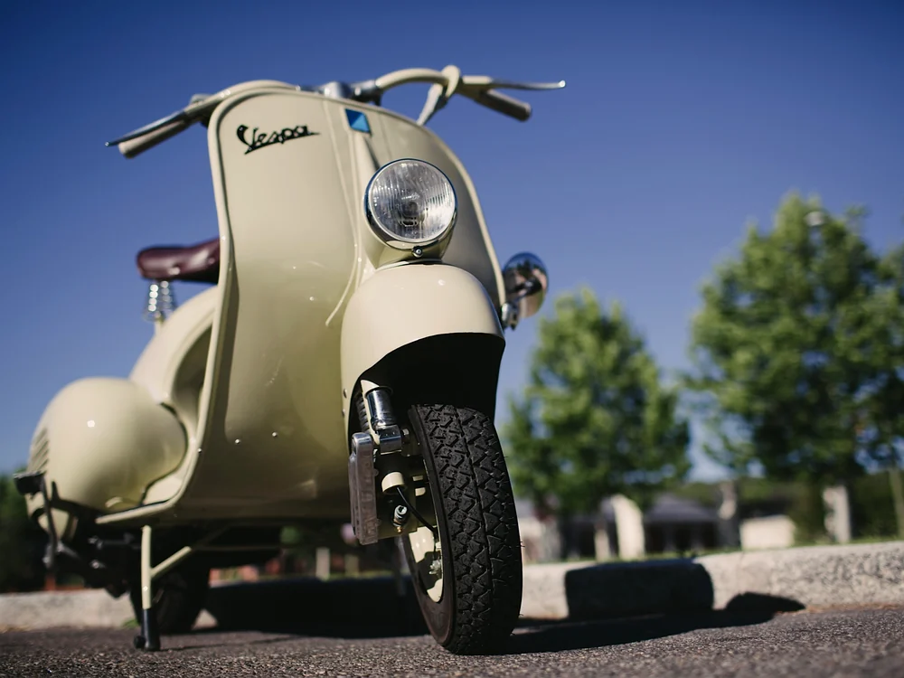 Detalle del faro bajo y la carrocería de una Vespa 125 N de 1955 restaurada