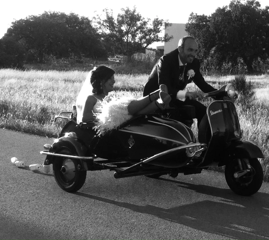 Novios en una Vespa con sidecar durante su boda, en blanco y negro