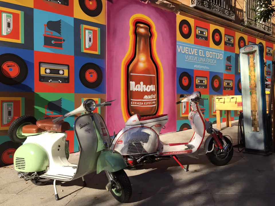 Tres Vespas de colores ante una escenografía de campaña