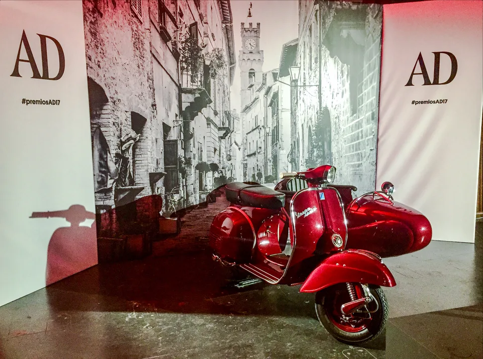 Vespa roja con sidecar como pieza central de un espacio para fotografías