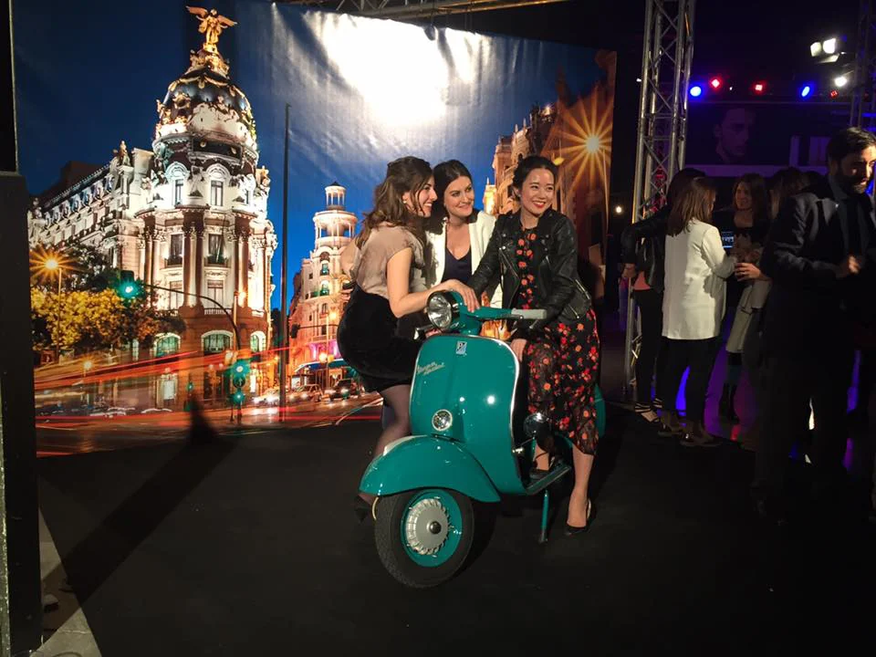 Invitadas junto a una Vespa verde en un evento de interior