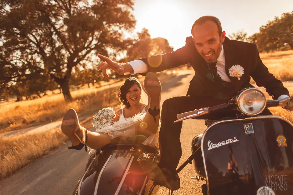 Pareja de novios en una Vespa con sidecar bajo la luz del atardecer