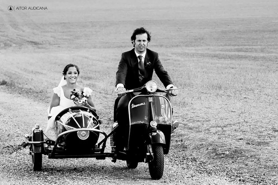 Pareja en una Vespa con sidecar en un paisaje abierto, en blanco y negro