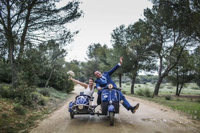 Pareja viajando en una Vespa azul con sidecar por un camino de campo