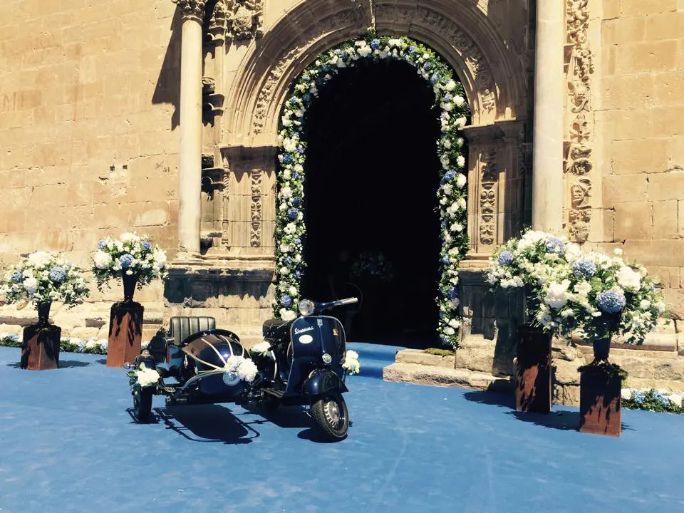 Vespa con sidecar decorada para una boda ante la entrada de una iglesia